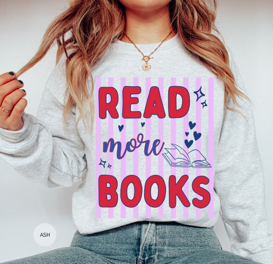Woman wearing an ash gray Read More Books sweatshirt featuring bold red and navy lettering, pink vertical stripes, hearts and an open-book illustration.