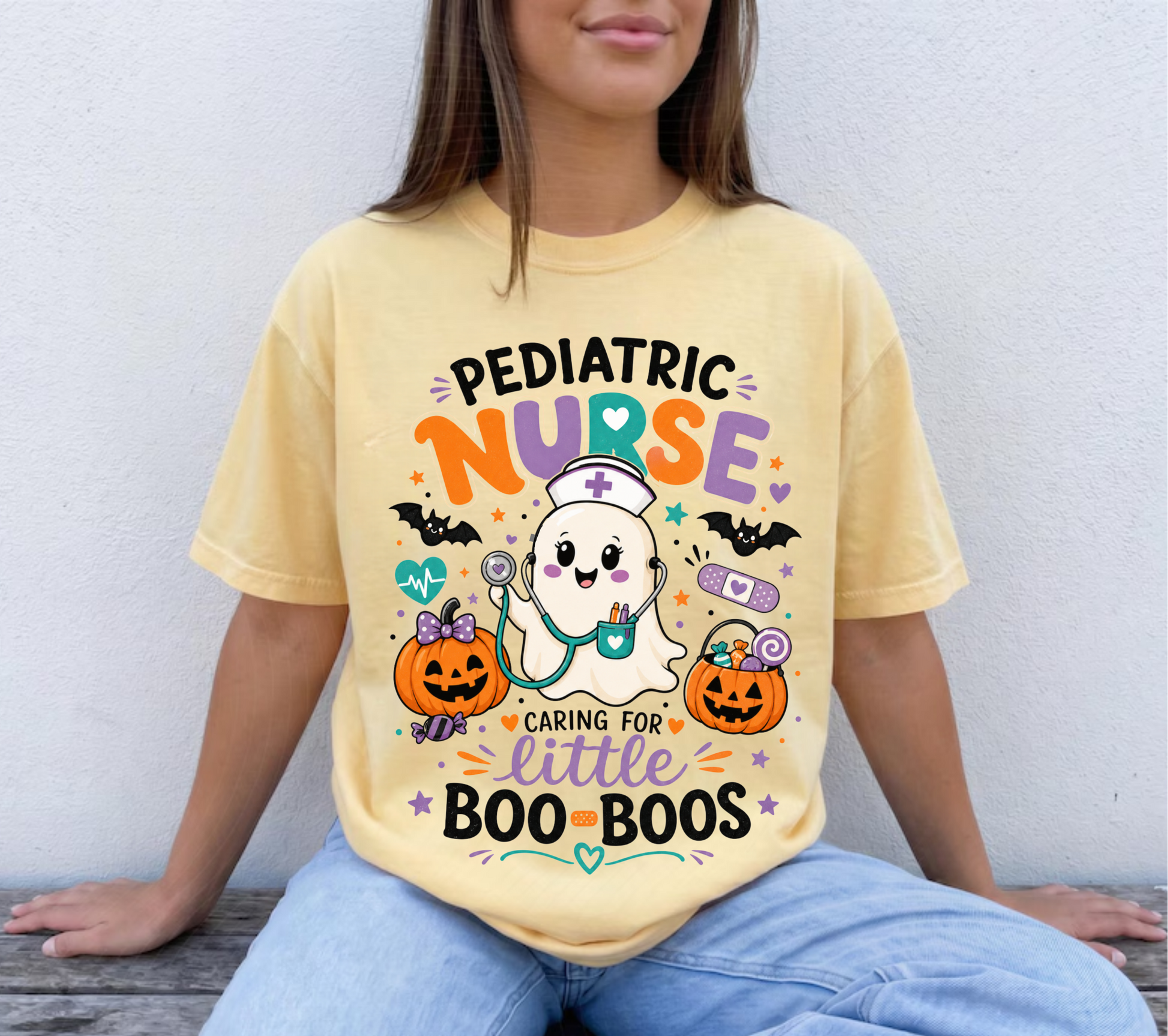 Cute Pediatric Nurse Halloween shirt featuring a smiling ghost nurse with pumpkins and the phrase "Caring for Little Boo-Boos" on a Comfort Colors t-shirt.