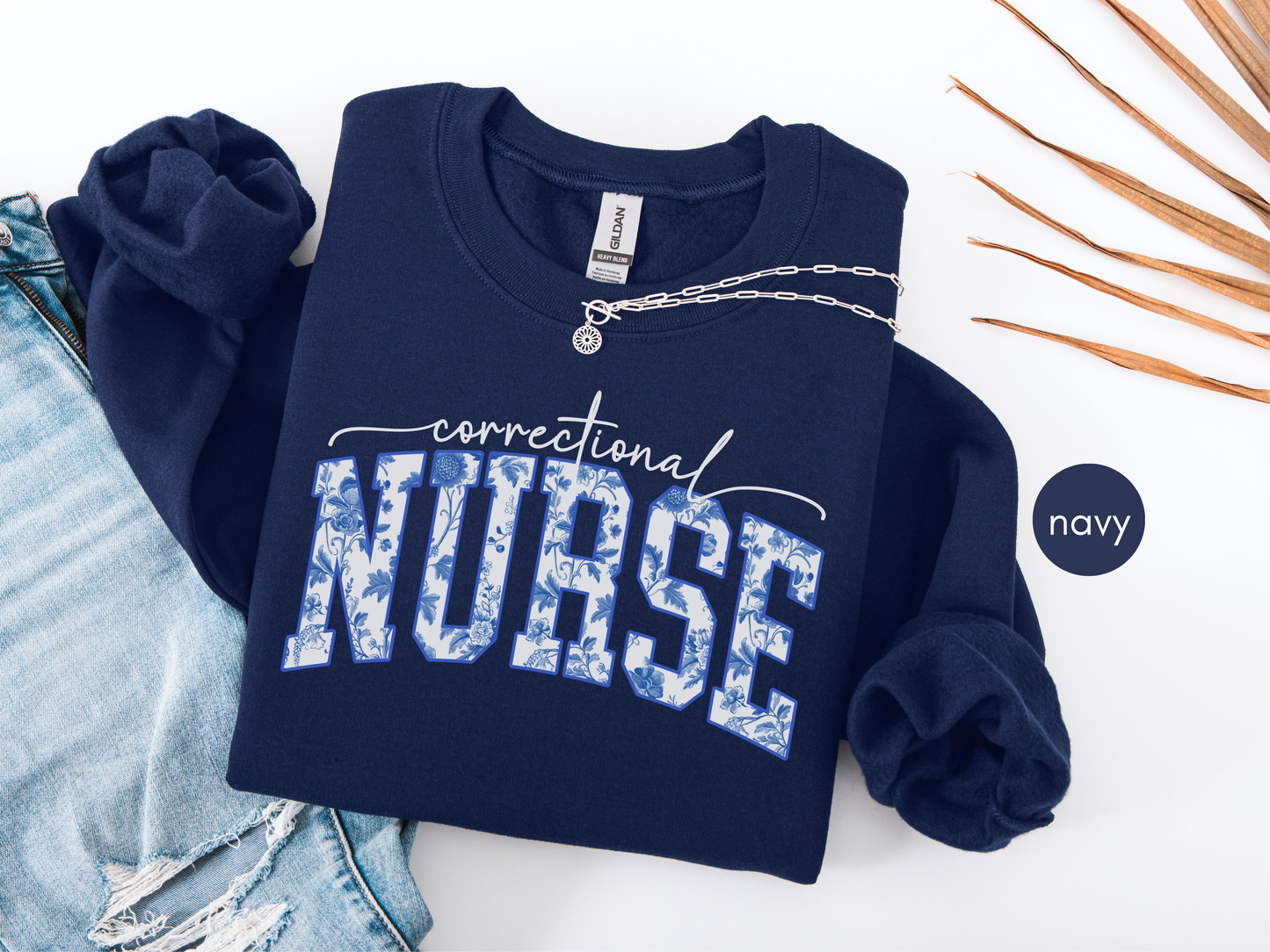Correctional nurse sweatshirt in navy blue with blue floral lettering, folded flat lay style