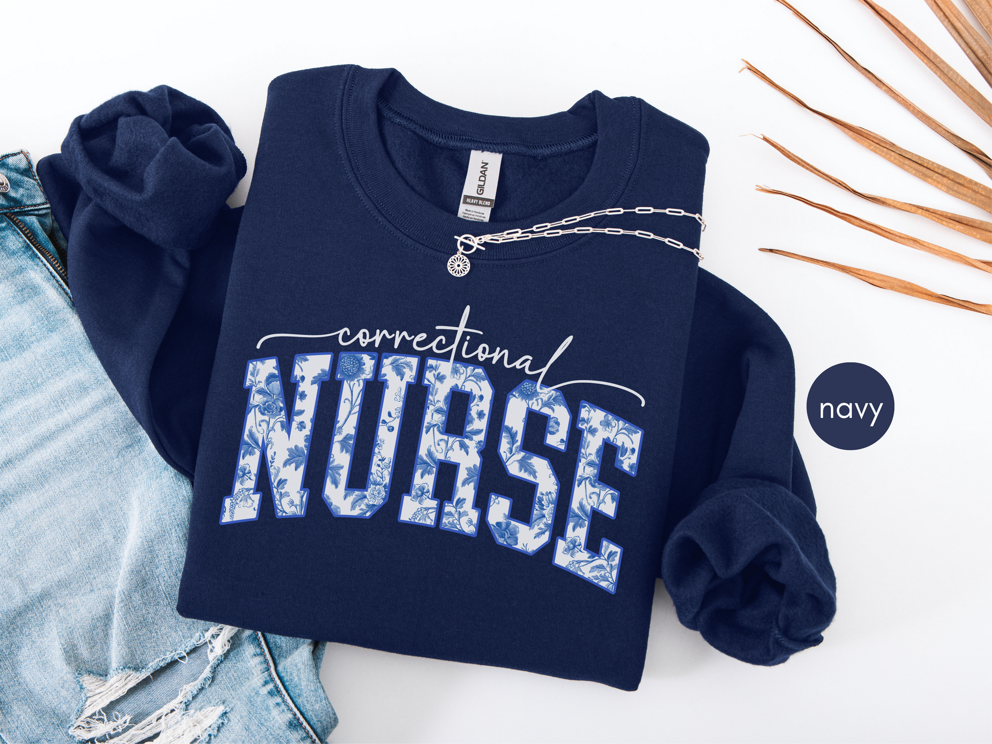 Correctional nurse sweatshirt in navy blue with blue floral lettering, folded flat lay style