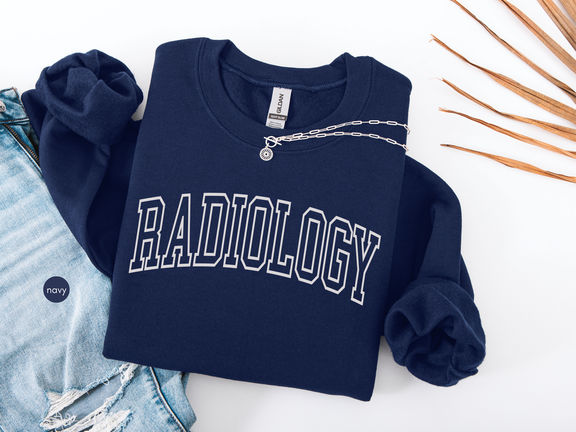 Navy radiology sweatshirt with collegiate-style lettering laid flat with denim and accessories