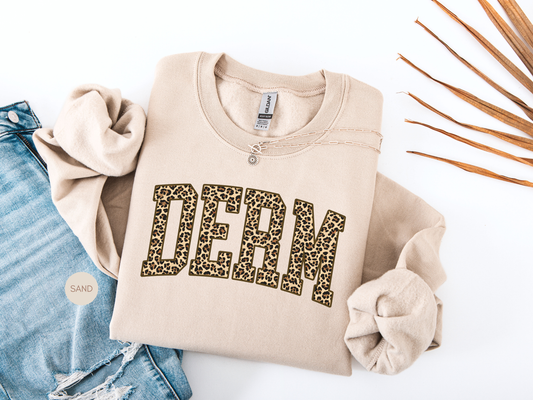 Beige DERM leopard print sweatshirt styled flat lay, perfect gift for dermatology nurse