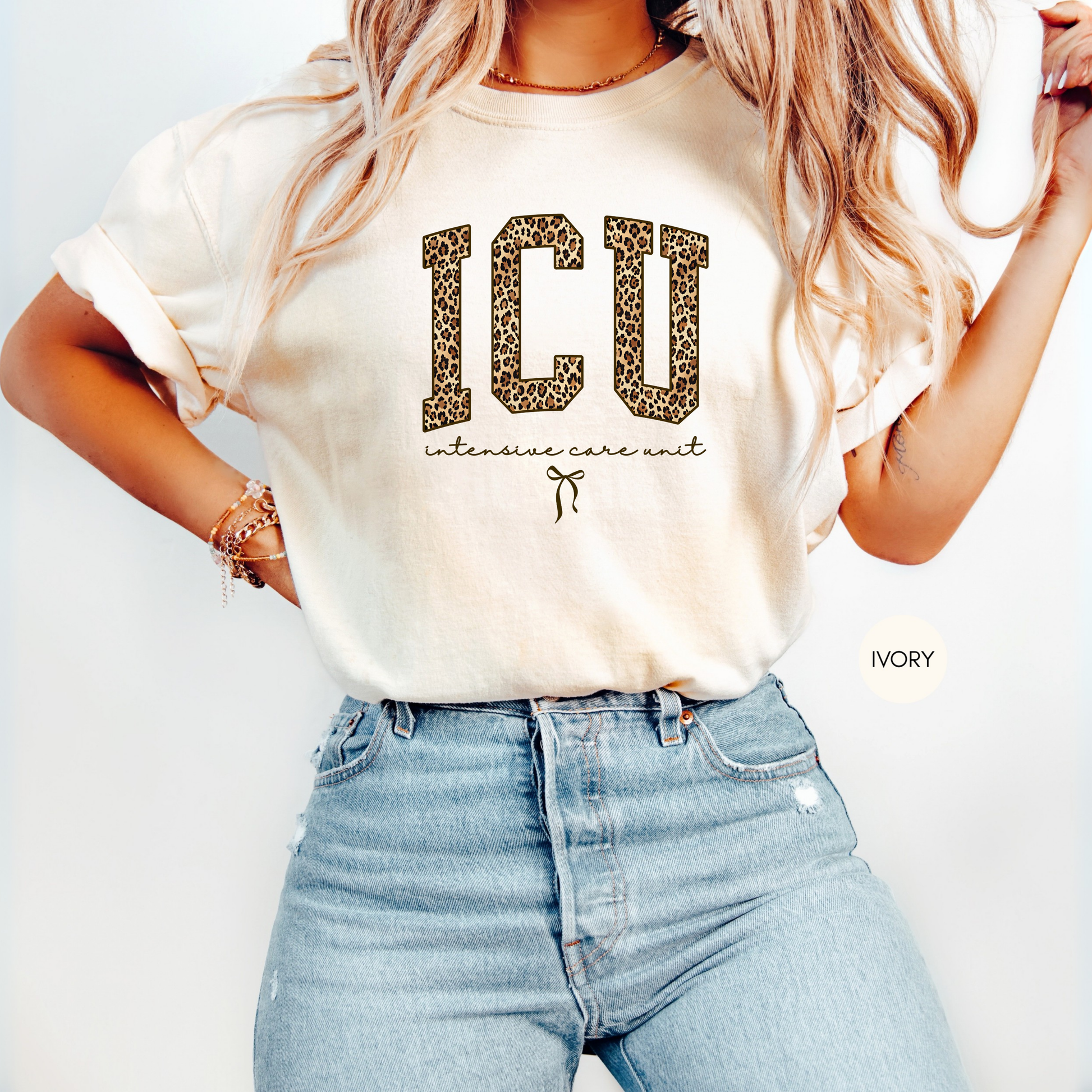 Woman wearing ivory ICU nurse leopard graphic t-shirt styled with jeans, intensive care unit nurse apparel gift idea.