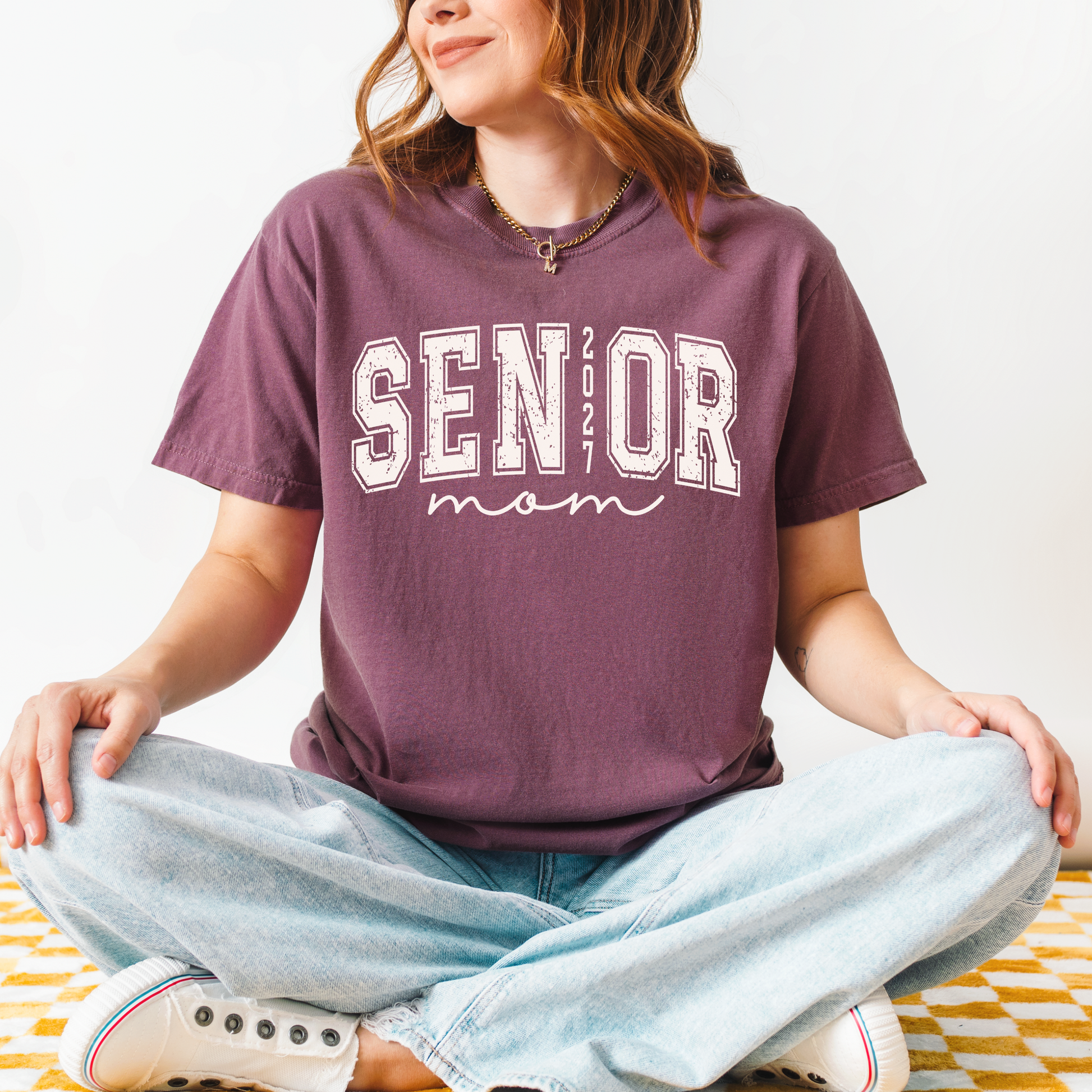 Senior Mom 2027 varsity graphic t-shirt on Comfort Colors garment-dyed tee for proud Class of 2027 moms attending football games, Senior Night, and graduation.