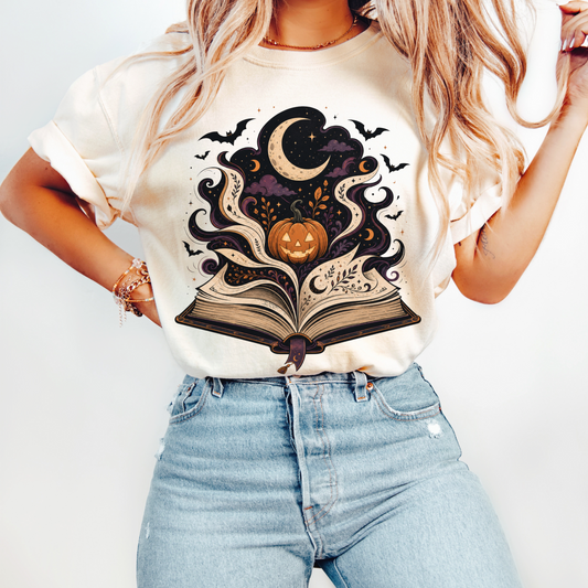 Halloween book lover shirt featuring an open magical book with pumpkin moon and bats