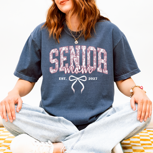 Senior Mom Est. 2027 Comfort Colors navy blue shirt featuring a pink toile varsity design with bow, perfect for Class of 2027 graduation celebrations and senior moms.